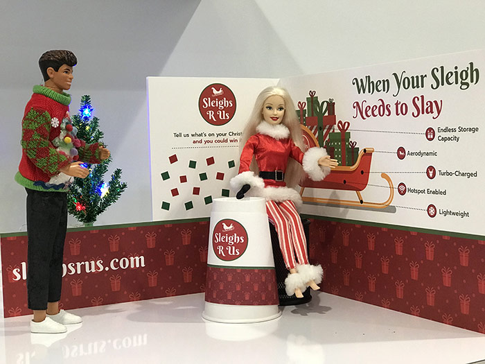 Ken and Barbie dolls in tiny Christmas themed tradeshow booth